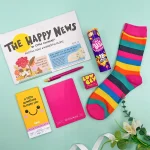Bright rainbow letterbox gift with colourful socks, sweets, notebook and positive newspaper
