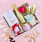 18th birthday gift box for her with mini Prosecco, birthday cake popcorn, Prosecco gummy sweets, chocolate hearts, birthday candle, bath bomb and gold party crown.