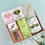 Everyday gift hamper for him featuring peppermint tea, mixed nuts, Italian olives, salted caramel biscuits, a herb growing kit, notebook, and pen in a reusable gift box.